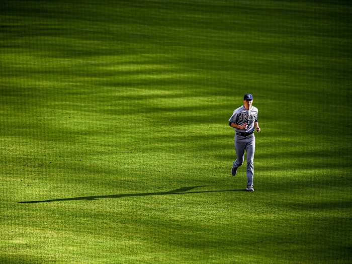 A Rays pitcher runs in the outfield